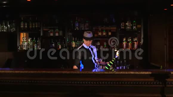 年轻有魅力的专业酒吧男调酒师用两瓶酒做酷专业令人惊奇的把戏视频的预览图