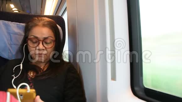 亚洲泰国老妇人坐在火车上玩手机听音乐视频的预览图