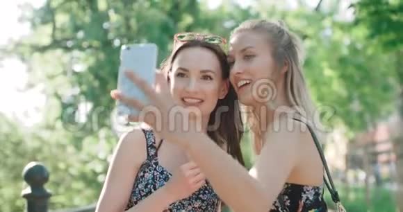 两个年轻快乐的女孩在户外玩和自拍的肖像视频的预览图