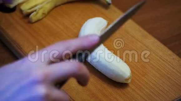 女人在家庭厨房的木制厨房板上切香蕉视频的预览图