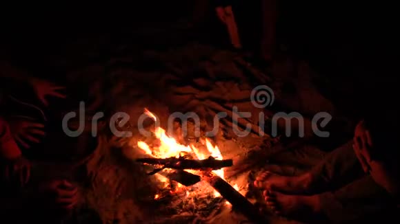 一个人在海边的篝火旁用原木在沙滩上画画4KUHD视频的预览图