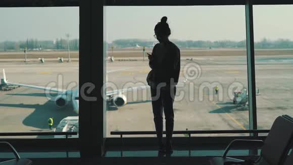 站在机场候机楼窗口的女孩视频的预览图