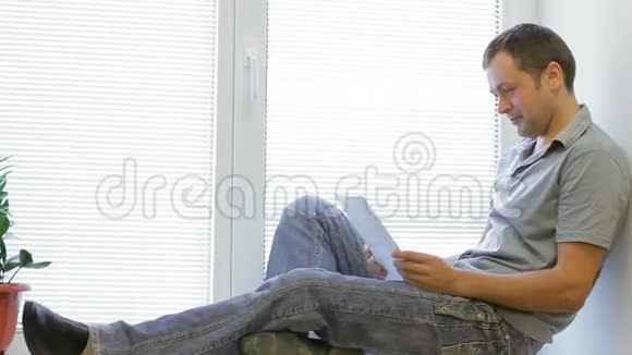 一个男人坐在窗户上看到一张女孩的照片视频的预览图