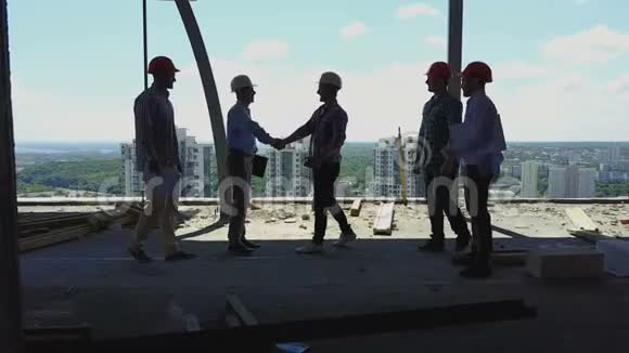 建筑工人团队与业主在施工现场的握手承包商小组会议视频的预览图