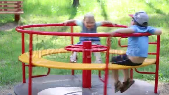 快乐的男孩和女孩在夏日公园的旋转木马上玩得开心视频的预览图