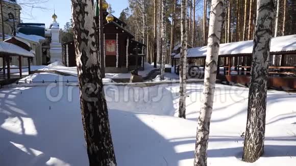 在俄罗斯冬季古老的教堂倾斜着山上有白色的树木冬天森林里的神庙视频的预览图