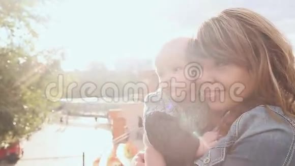 母亲抱着儿子在阳光下的城市街道上视频的预览图