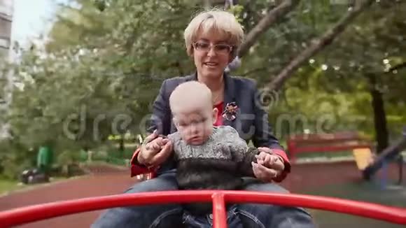 奶奶和宝宝夏天高兴地在公园里旋转旋转旋转木马视频的预览图