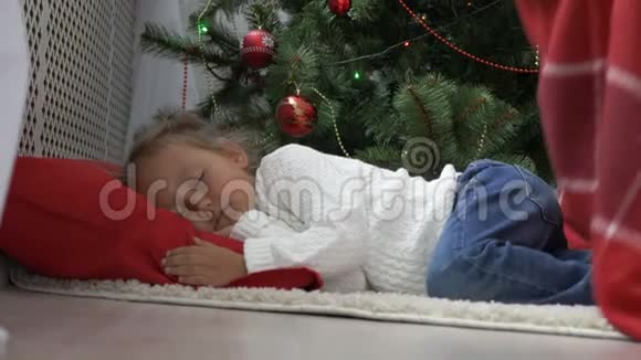 早上睡在圣诞树下的可爱小女孩视频的预览图