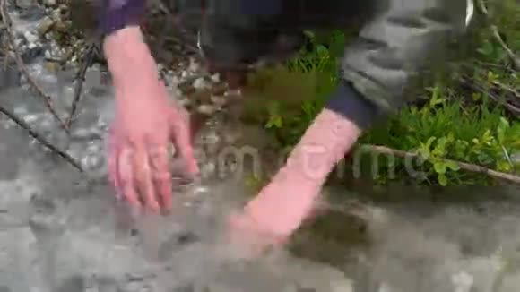 一个少年男孩在森林小溪里洗手小溪里的水又冷又干净手冻在冷水里乌云密布视频的预览图