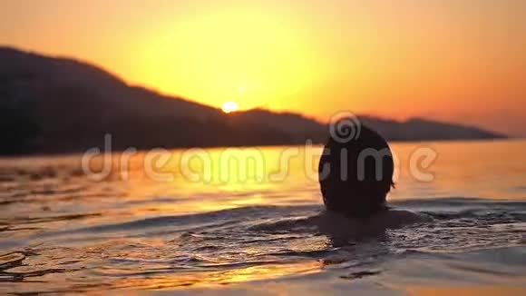 人类在日落时游泳在缓慢的运动中溅海1920x1080视频的预览图
