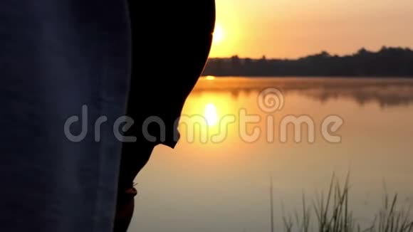 年轻孕妇在日落的湖岸做瑜伽运动视频的预览图
