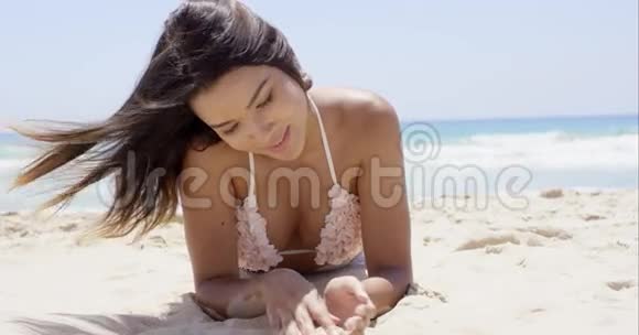 黑发女孩躺在沙滩上视频的预览图
