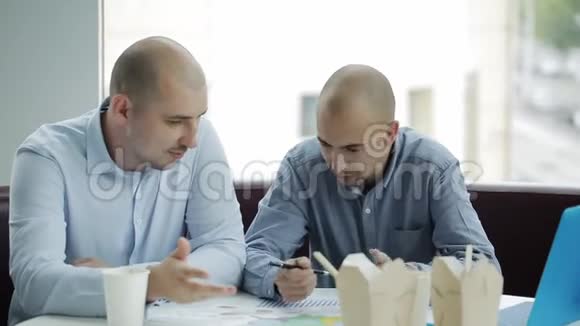 两个商人在午餐时讨论这个项目两个商人吃着中国面条讨论一个商业计划视频的预览图