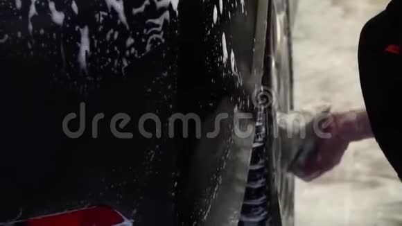 洗车一个洗车工洗车一个男人用泡沫海绵洗汽车特写镜头慢动作视频的预览图