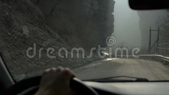 在雾蒙蒙的天气里女孩在深谷中开车沿着道路行驶检查岩石视频的预览图