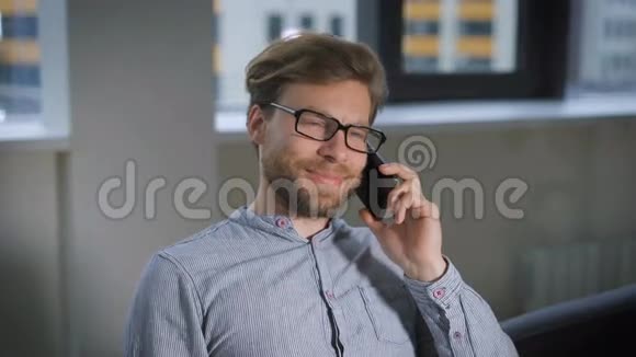 一个商人坐在接待处的沙发上脸上带着微笑在打电话视频的预览图