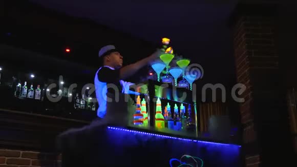 年轻有魅力的专业酒吧男调酒师用两瓶酒做酷专业令人惊奇的把戏视频的预览图