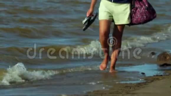 美丽的棕褐色的雌性脚沿着沙质海岸的边缘小波浪用温水刷新脚视频的预览图