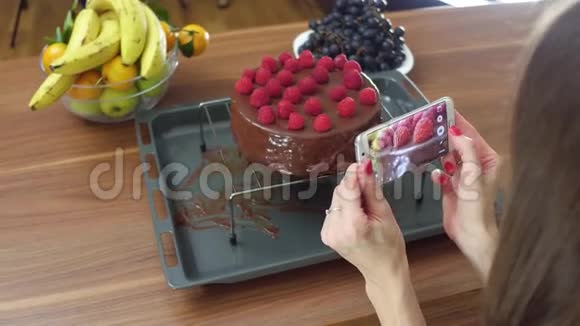 年轻女子在家里为她刚煮好的覆盆子蛋糕拍照业余烹饪和社交媒体分享概念视频的预览图