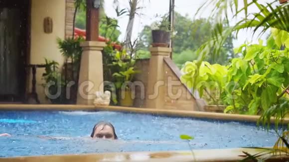 潮湿的白种人在度假时在游泳池里慢动作地泼水享受着下雨的乐趣1920x1080视频的预览图