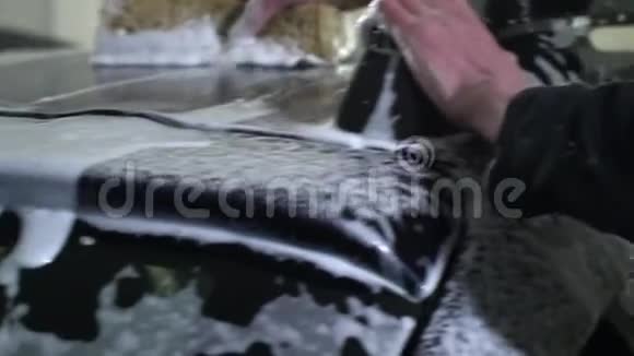 洗车一个洗车工洗车一个男人用泡沫海绵洗汽车特写镜头慢动作视频的预览图