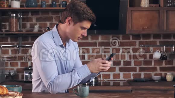 男性早餐在家使用智能手机视频的预览图