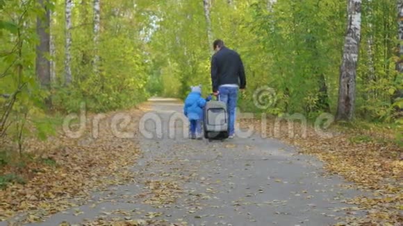带着手提箱的人和孩子走在森林小径上视频的预览图