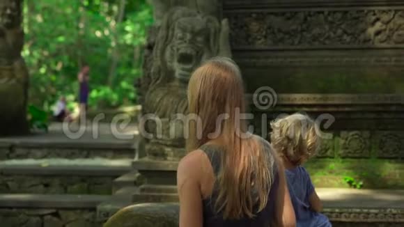 一名年轻女子和她的小儿子在印度尼西亚Ubud参观猴子森林生态公园的慢镜头视频的预览图