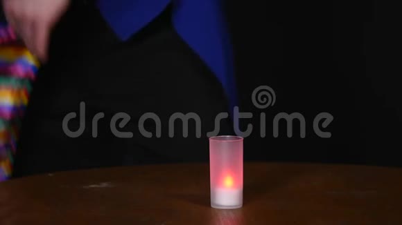 魔术师在黑暗的背景上用围巾和蜡烛表演魔术视频的预览图