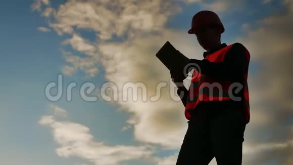 工人剪影工人建筑工人与红色头盔和牛仔裤衬衫附近的工业墙剪影生活方式工人视频的预览图