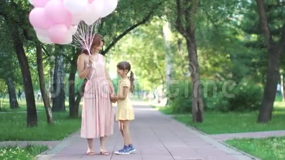 一位母亲和她的小女儿的肖像那个年轻女人手里拿着气球视频的预览图