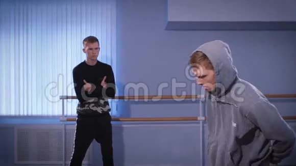 训练大厅里的两个年轻舞者穿着一件苏沃博尼毛衣的人在一次散场中做主要动作他的视频的预览图
