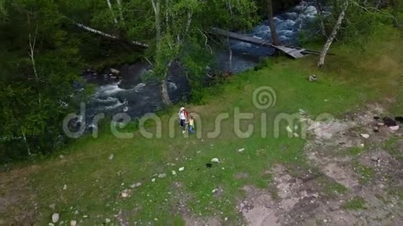 空中飞行一家人沿着山间的小溪散步体育妈妈带着孩子去远足西伯利亚阿尔泰视频的预览图