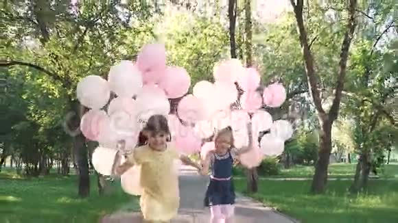 快乐无忧无虑的童年两个小女朋友牵着手牵着五颜六色的花跑过夏天的公园视频的预览图
