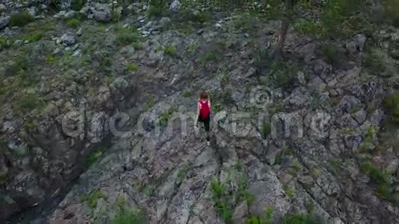 空中飞行带着背包的女孩游客偷偷地穿过岩石地形阿尔泰西伯利亚空中摄影机拍摄视频的预览图