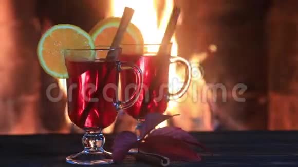两杯热覆盖葡萄酒与香料在木桌上壁炉视频的预览图