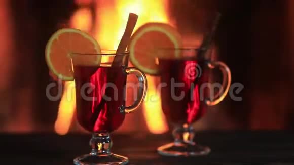 两杯热覆盖葡萄酒与香料在木桌上壁炉视频的预览图