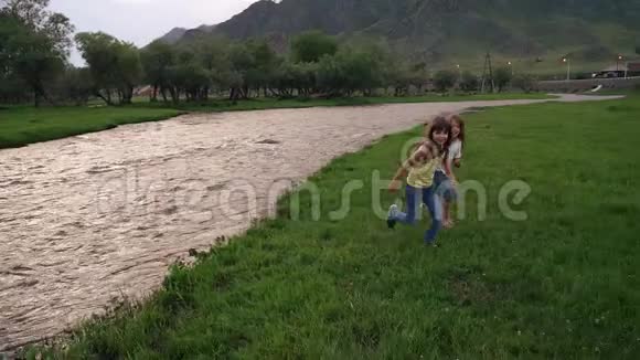 村里的孩子们两个小妹妹在河边的草地上跑来跑去慢动作视频的预览图