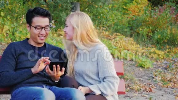青年男女在公园里聊天欣赏碑文高加索女人和韩国男人视频的预览图