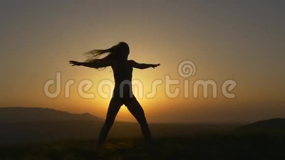 一位留着长发的妇女在夕阳下跳着舞嬉戏视频的预览图
