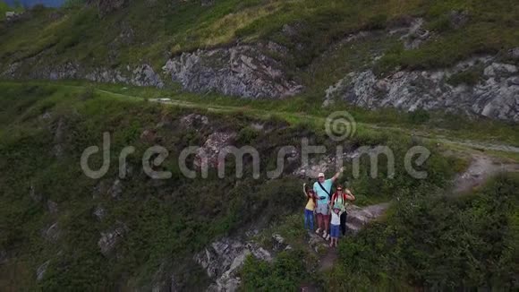 空中飞行幸福的一家人坐在悬崖边挥舞着手臂对着镜头微笑父亲视频的预览图