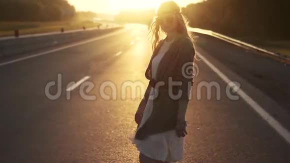 穿着嬉皮风格的女孩在路上戴太阳镜的年轻女人的肖像慢动作视频的预览图