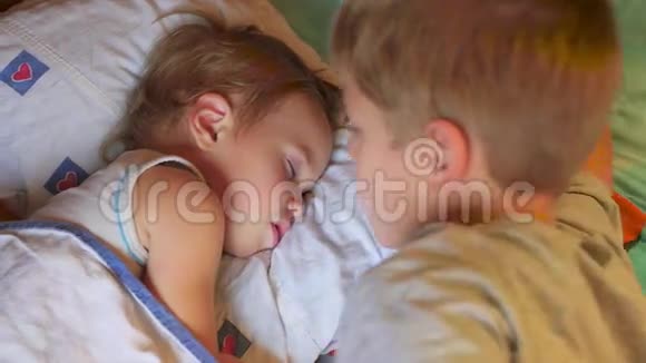哥哥在家里轻轻地吻了一下熟睡的弟弟视频的预览图