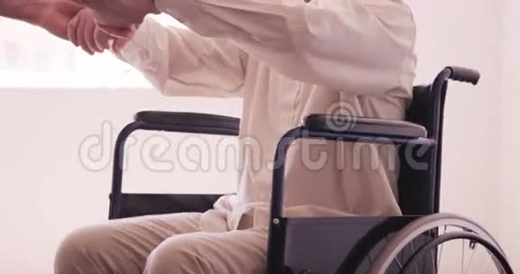 男医生协助老人从轮椅上站起来视频的预览图