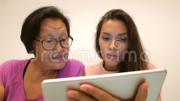 退休的亚洲妇女与年轻的混血女儿使用平板电脑小工具4k视频的预览图