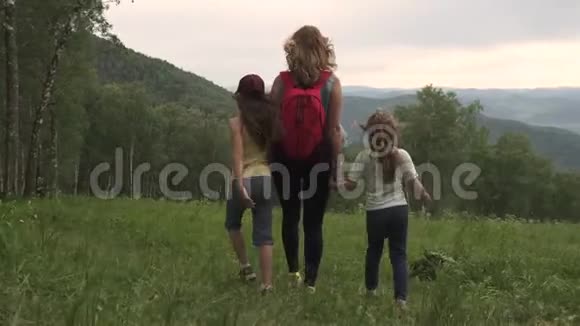 体育家庭穿越群山一位年轻的母亲带着背包带着她的孩子穿过一个视频的预览图