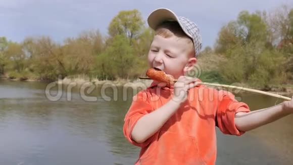 这孩子用牙齿吃香肠高兴地串在柳枝上视频的预览图