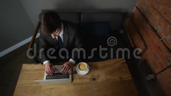 商人在笔记本电脑上工作在咖啡馆里喝咖啡顶部视图视频的预览图