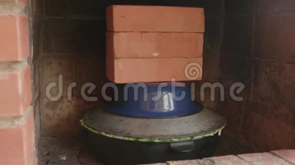 盛满食物的锅架在一个炉子里上面盖着盖子和砖块视频的预览图